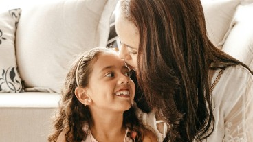 mãe e filha abraçadas junto ao sofá