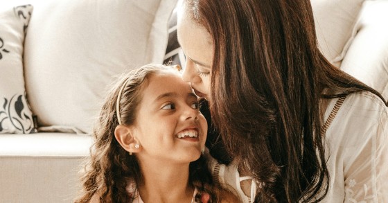 mãe e filha abraçadas junto ao sofá
