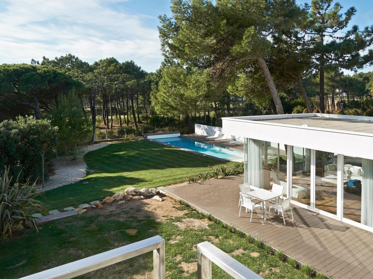 The house links directly to a golf course behind the trees