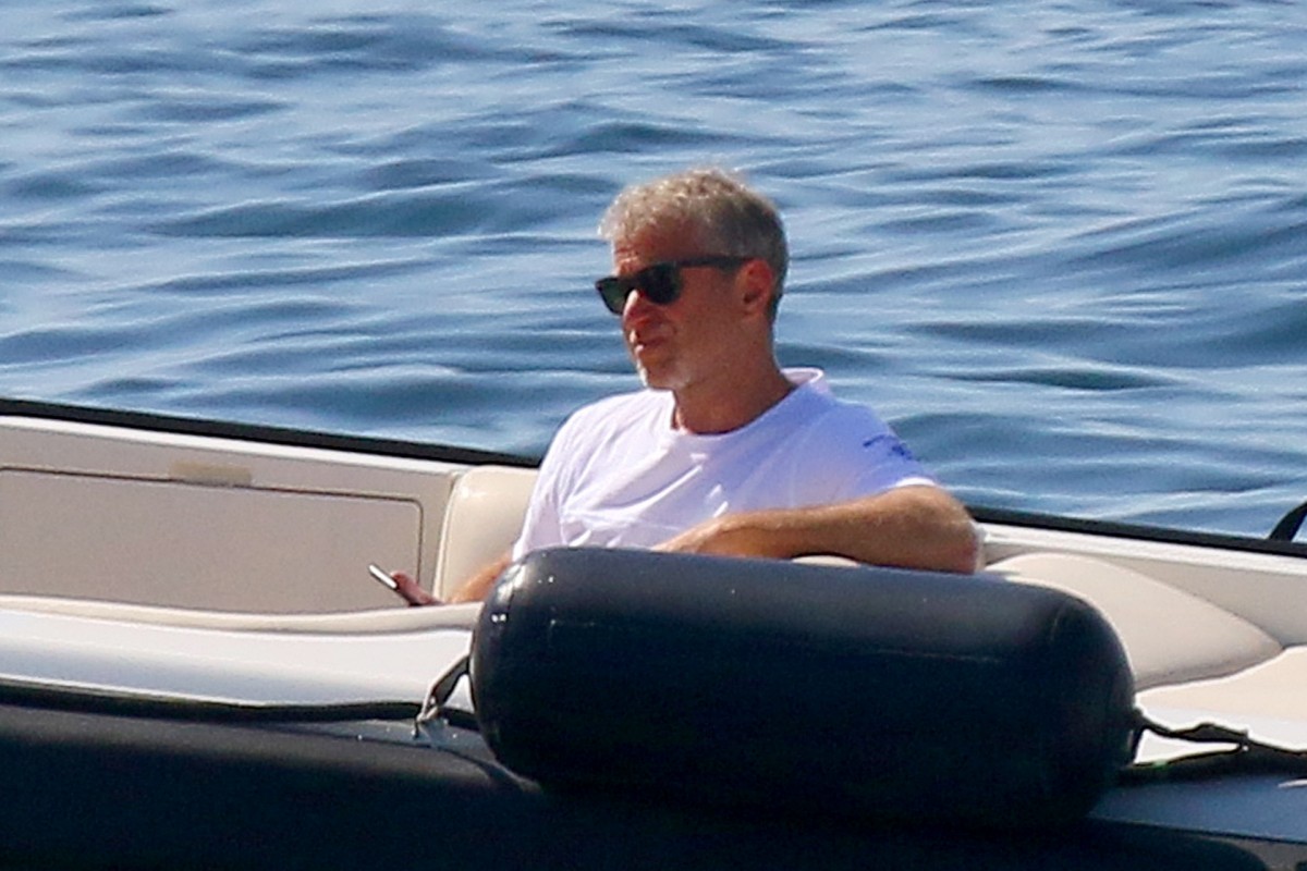 Abramovich sentado descontraído num iate, com o mar azul de fundo