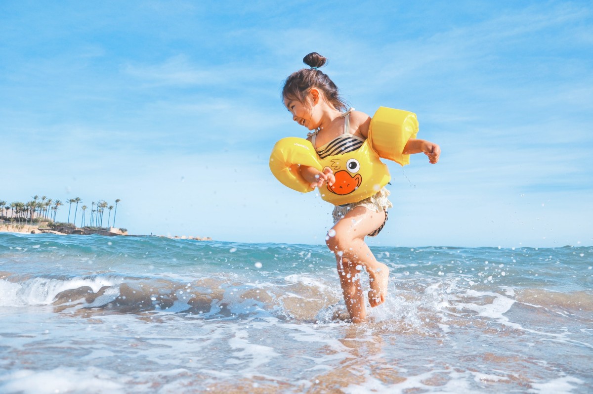Menina com bóias na praia