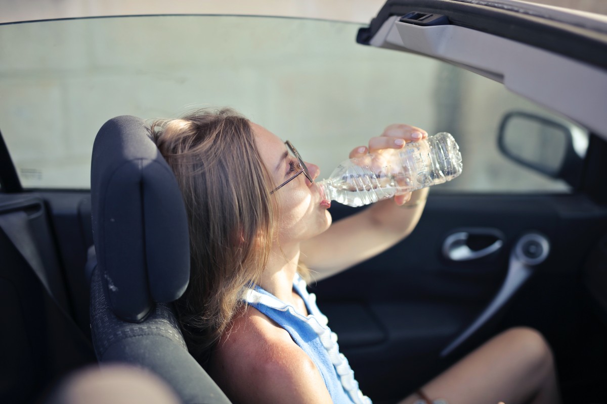 Mulher a beber água no carro