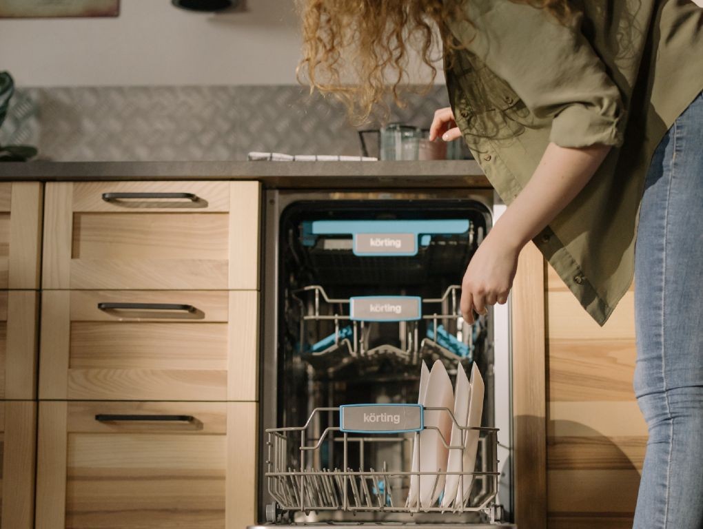 Rapariga a colocar pratos na máquina da loiça