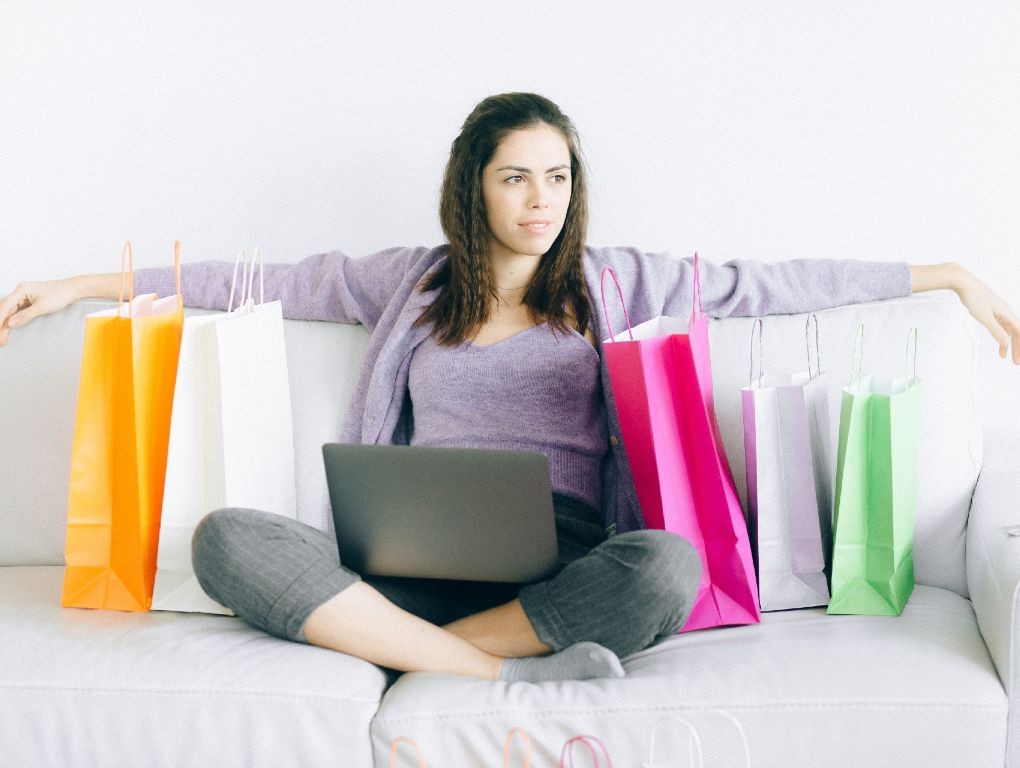 Mulher no sofá com compras e portátil