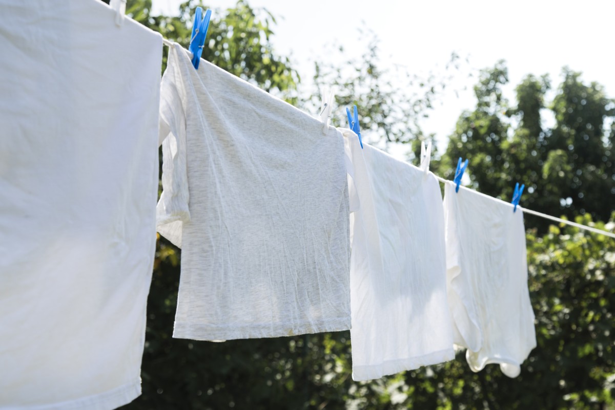 Roupas de venda de garagem para venda penduradas em cabides ao ar livre