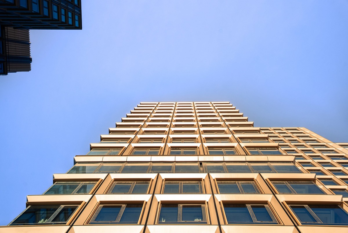 Las fachadas están revestidas con paneles de aluminio biselados que enmarcan las ventanas y generan un juego constante de reflejos.