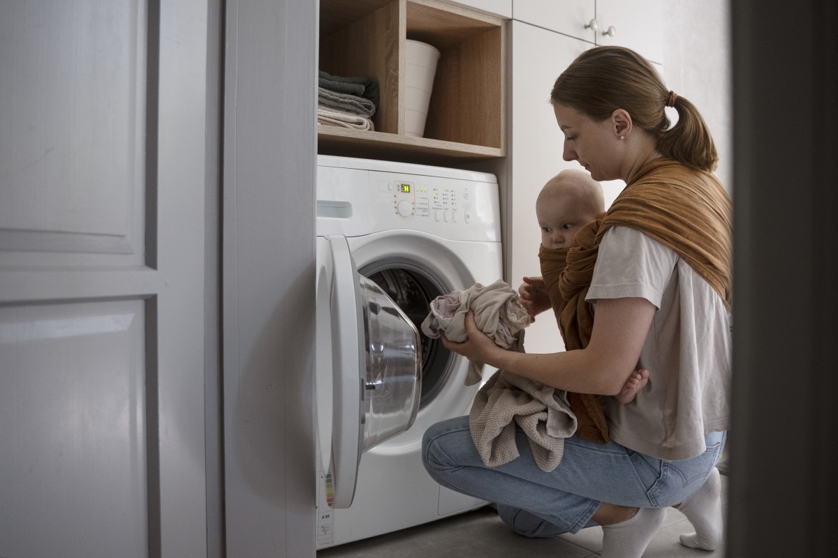 Mãe a colocar roupa na máquina