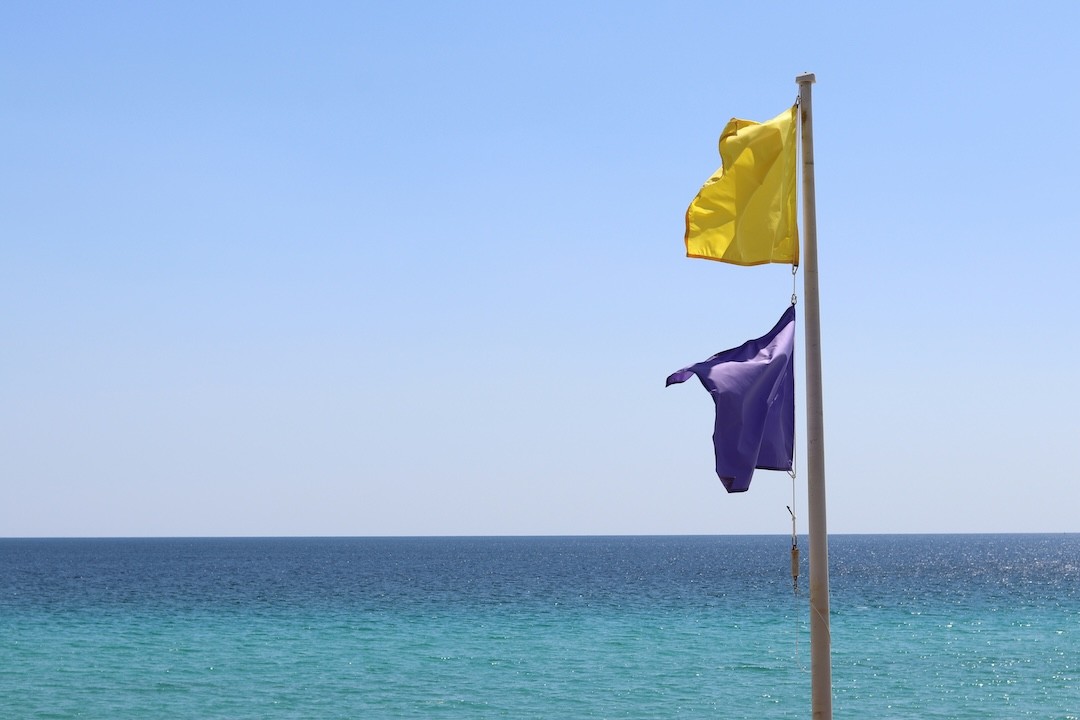 bandeira amarela e roxa na praia