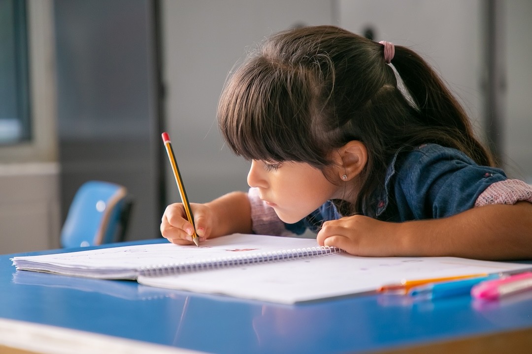 criança a escrever num caderno