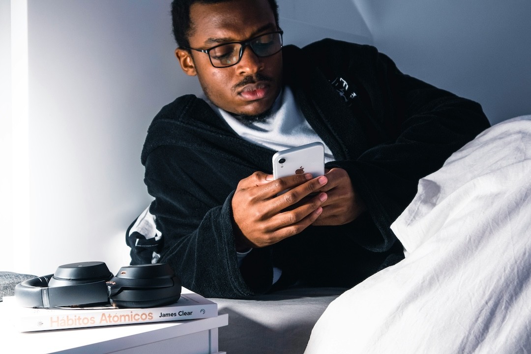 jovem com telemóvel na cama