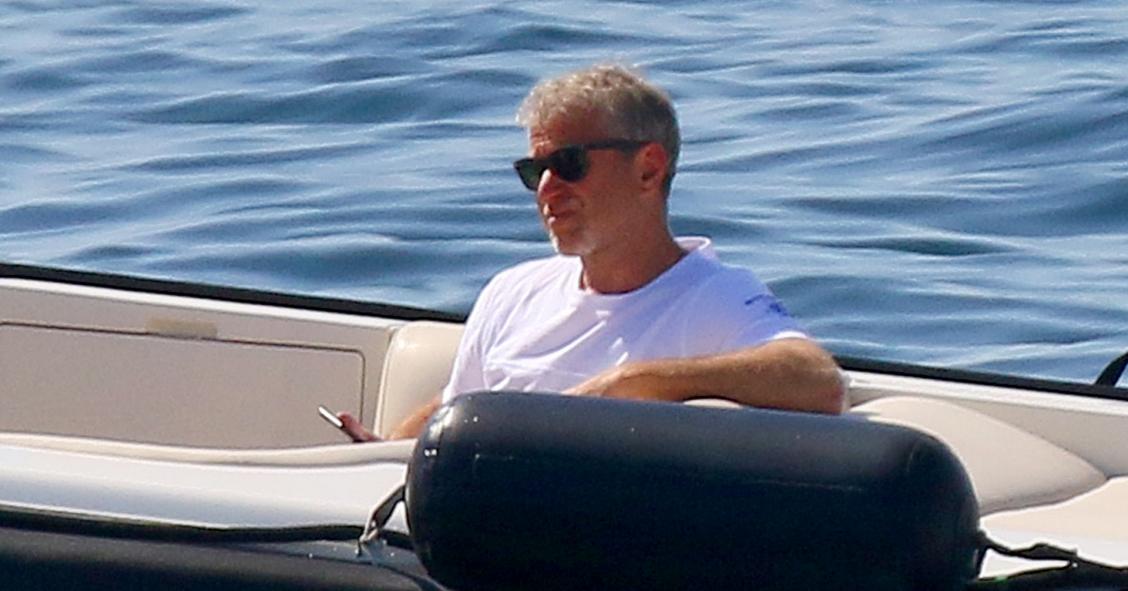 Abramovich sentado descontraído num iate, com o mar azul de fundo