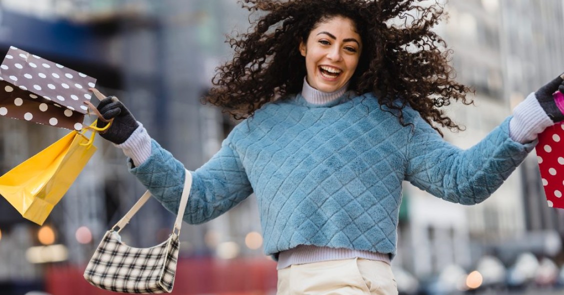 Mulher a saltar com sacos de compras