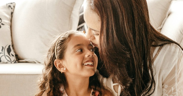 mãe e filha abraçadas junto ao sofá