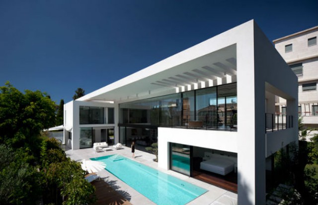 no exterior da casa, ao longo da fachada principal, existe uma piscina