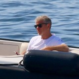Abramovich sentado descontraído num iate, com o mar azul de fundo