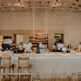 La panadería se articula alrededor de un mostrador en forma de U construido con tierra compactada, una técnica ancestral reinterpretada con elegancia contemporánea.